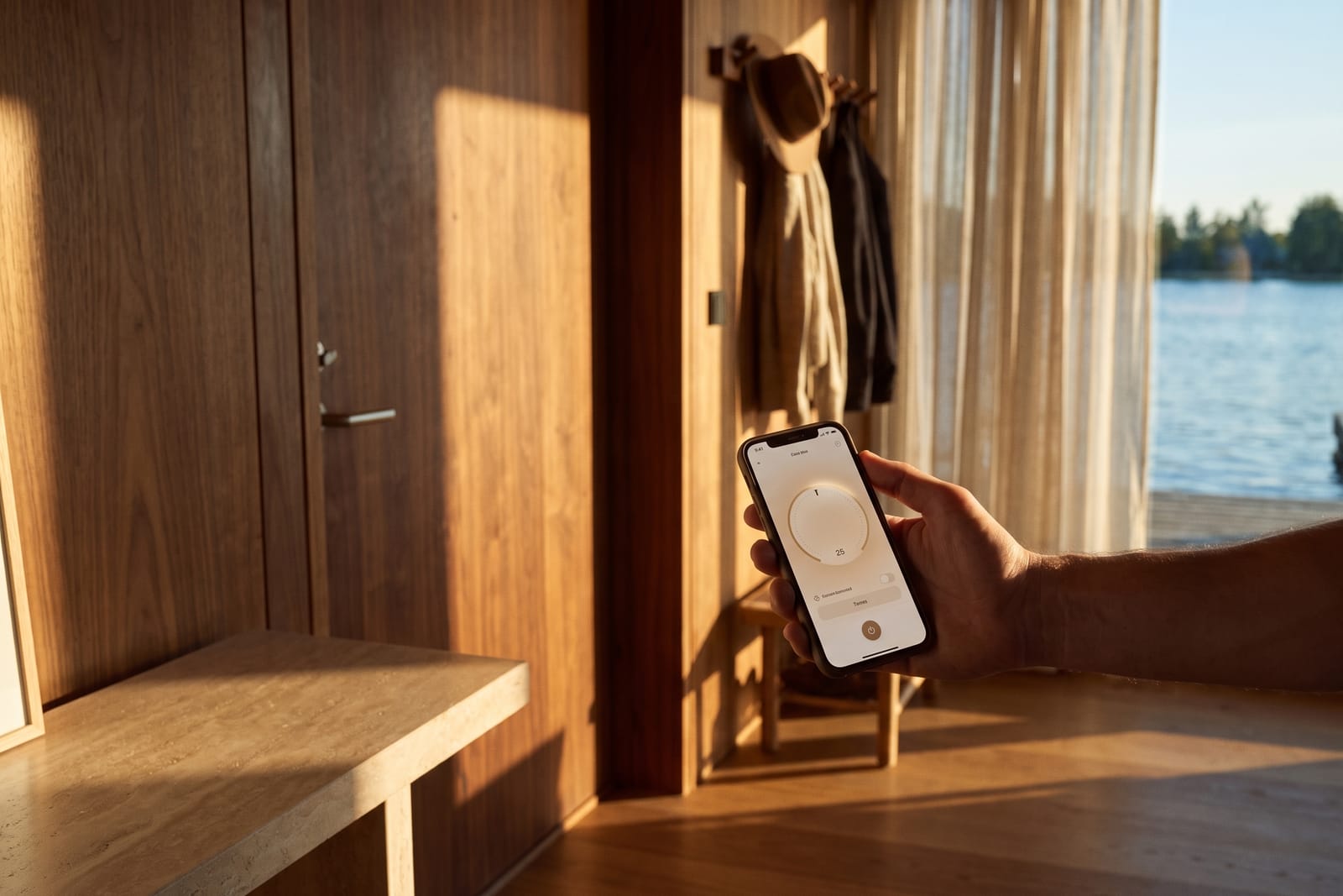 Eine Hand hält im Flur ein Handy mit einer Bedienungs-App