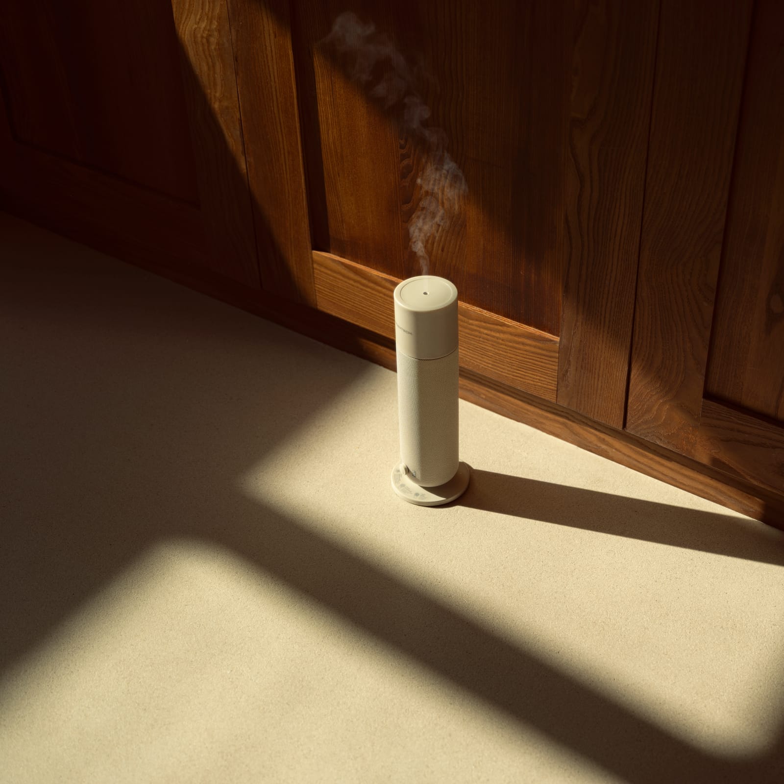 Smart Aroma Diffuser 2 mit feinem Duftnebel auf einer Steinarbeitsplatte im Sonnenlicht, dahinter Nussbaumfronten